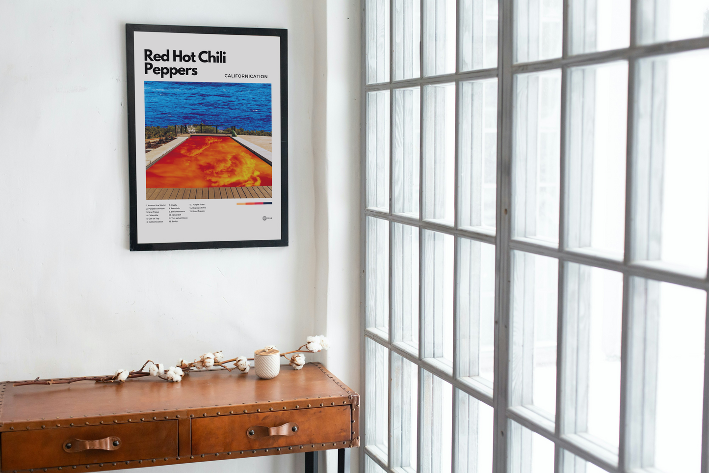 Framed Red Hot Chili Peppers poster on a wall next to a wooden desk with decor items.