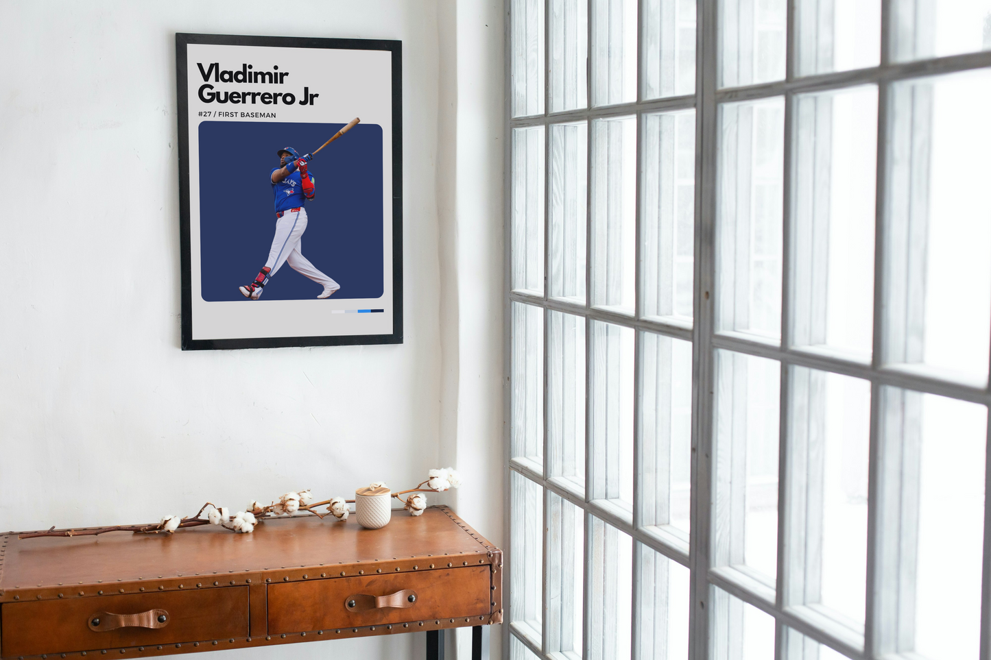 Framed sports poster of Vladimir Guerrero Jr. on a wall next to a wooden desk.