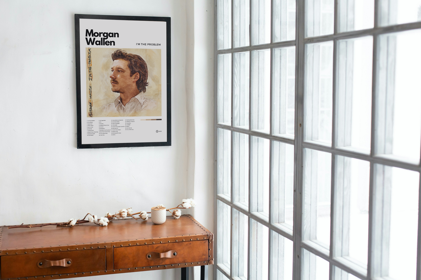 Framed poster of Morgan Wallen on a wall above a wooden desk with a window in the background.