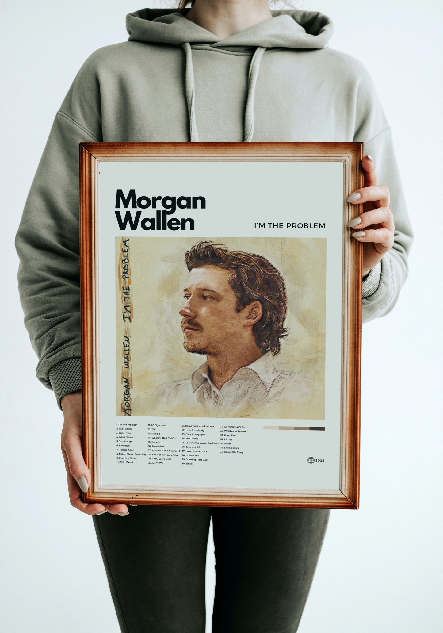 Person holding a framed poster of Morgan Wallen with album cover and text.