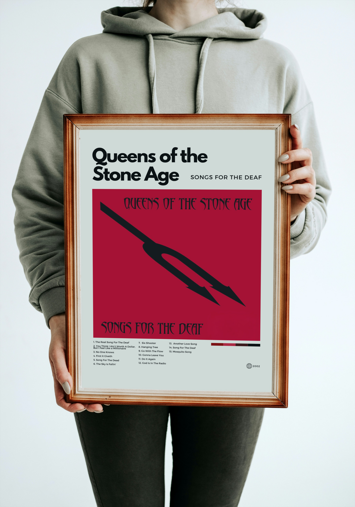 Person holding a framed album cover of 'Songs for the Deaf' by Queens of the Stone Age.