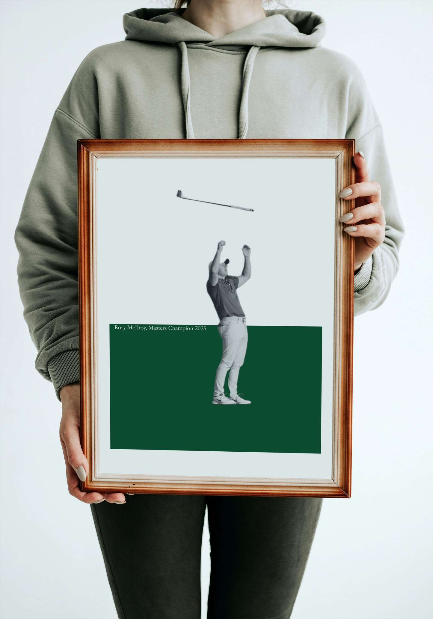 Person holding a framed print of a Rory McIlroy on a green background