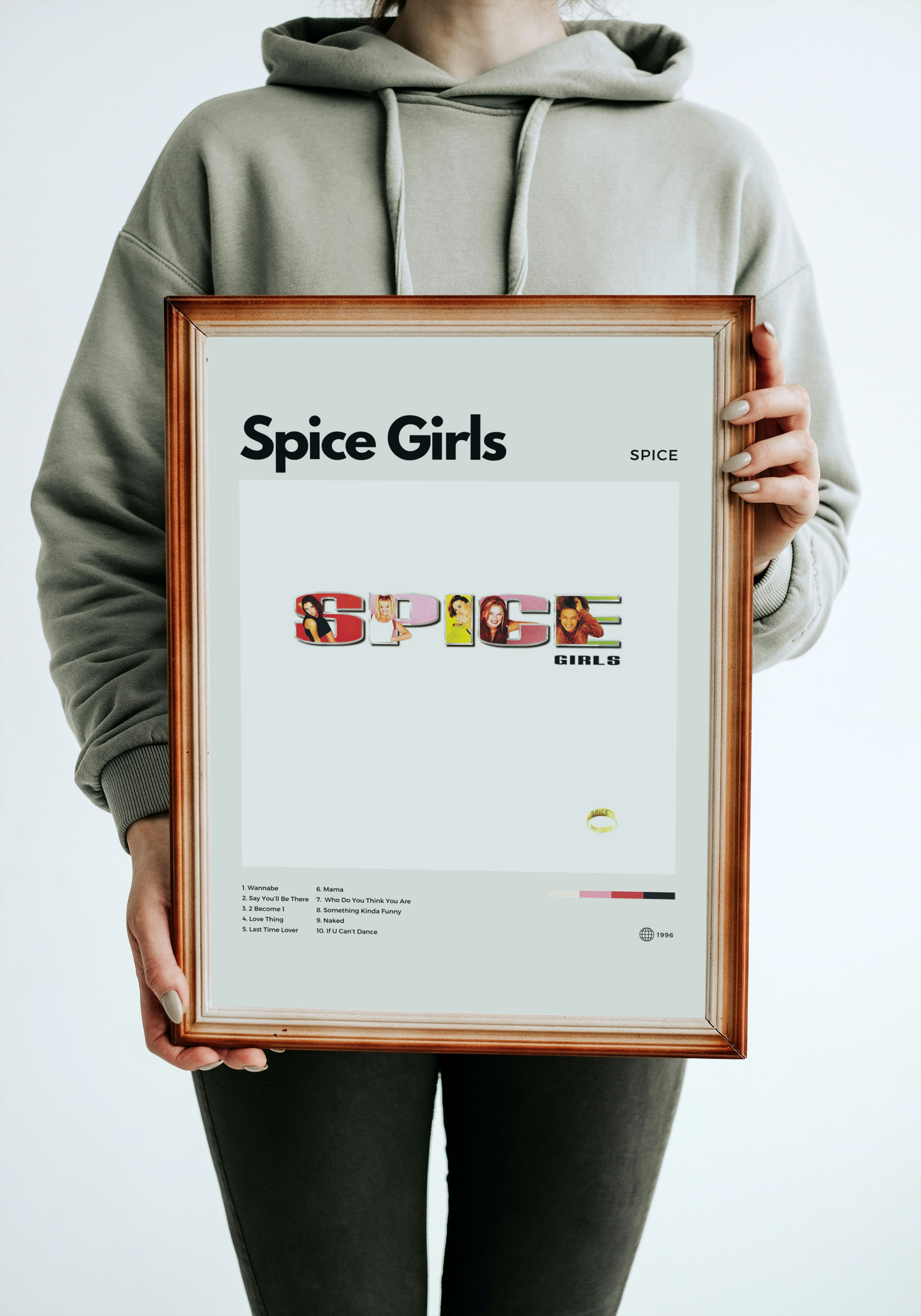 Person holding a framed 'Spice Girls' poster with a plain background