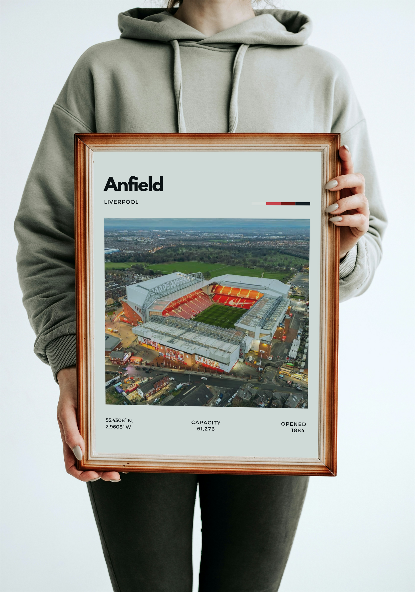 Person holding a framed print of Anfield stadium with a neutral background