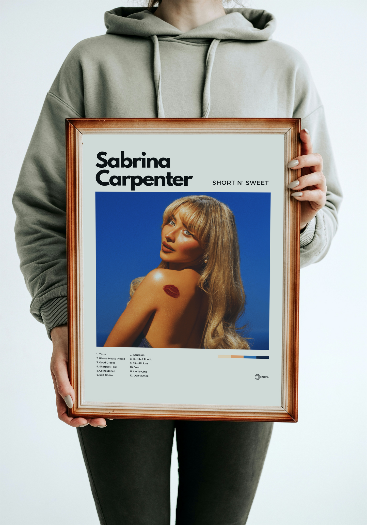 Person holding a framed poster of Sabrina Carpenter with a blue background