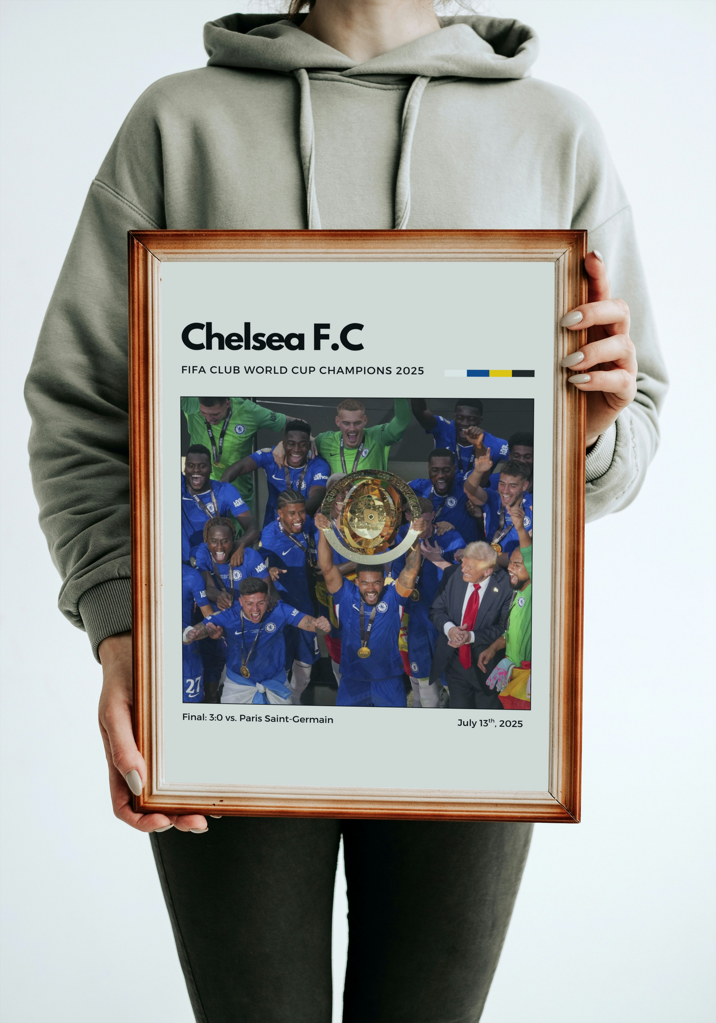 Person holding a framed poster of Chelsea F.C. celebrating a World Cup victory.