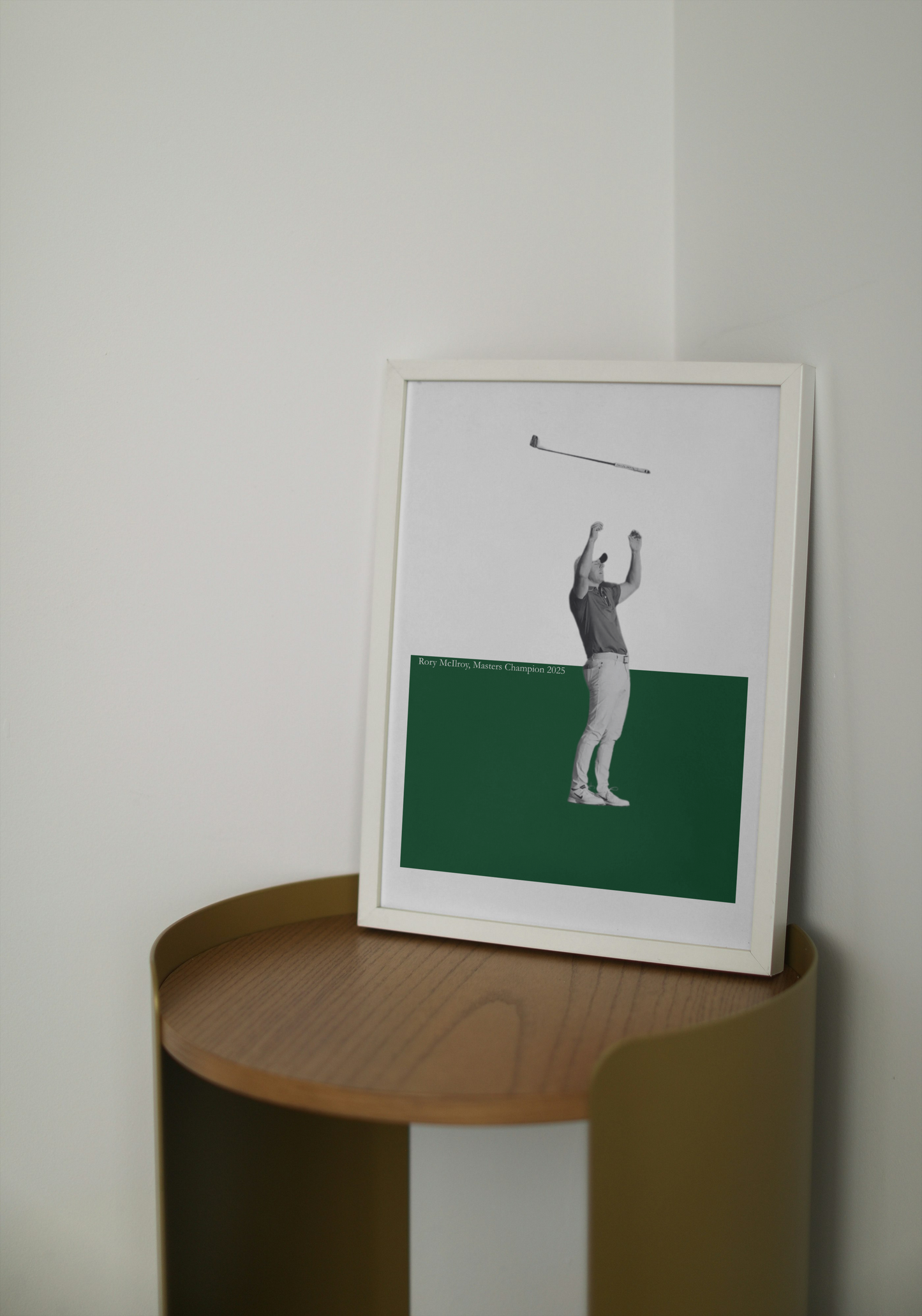 Framed artwork of Rory McIlroy on a wooden side table against a plain wall.