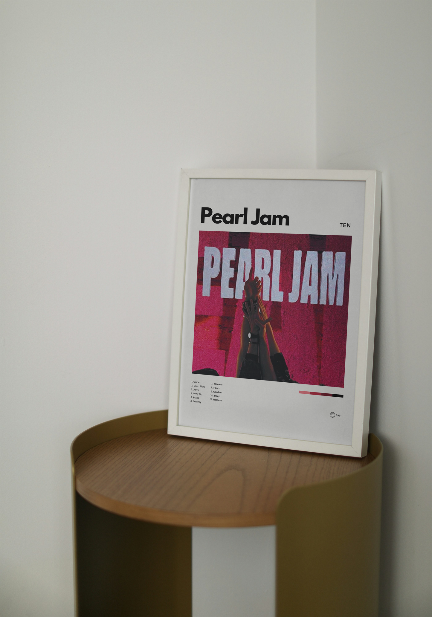 Framed Pearl Jam poster on a wooden shelf against a white wall