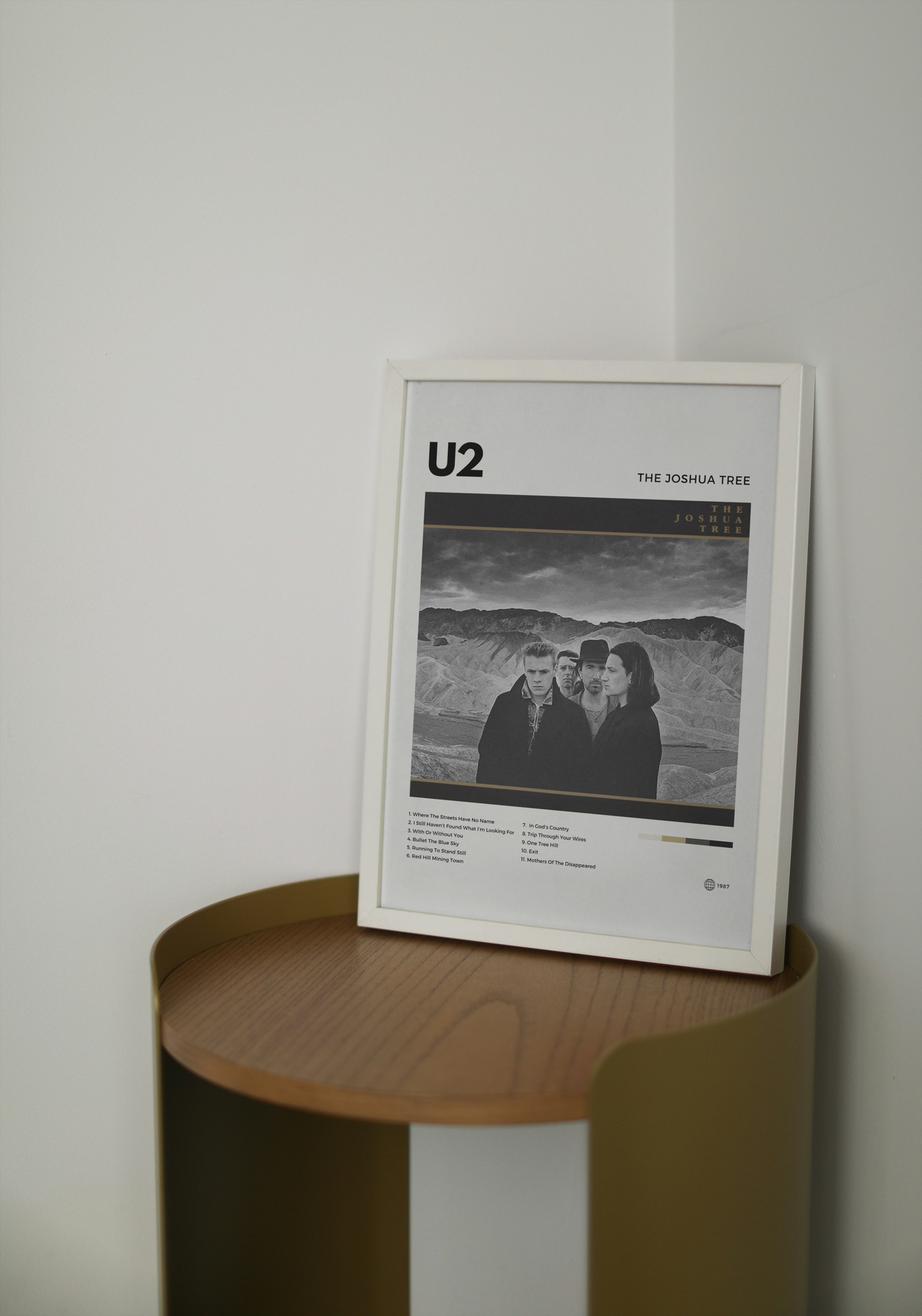 Framed U2 poster on a wooden side table against a white wall