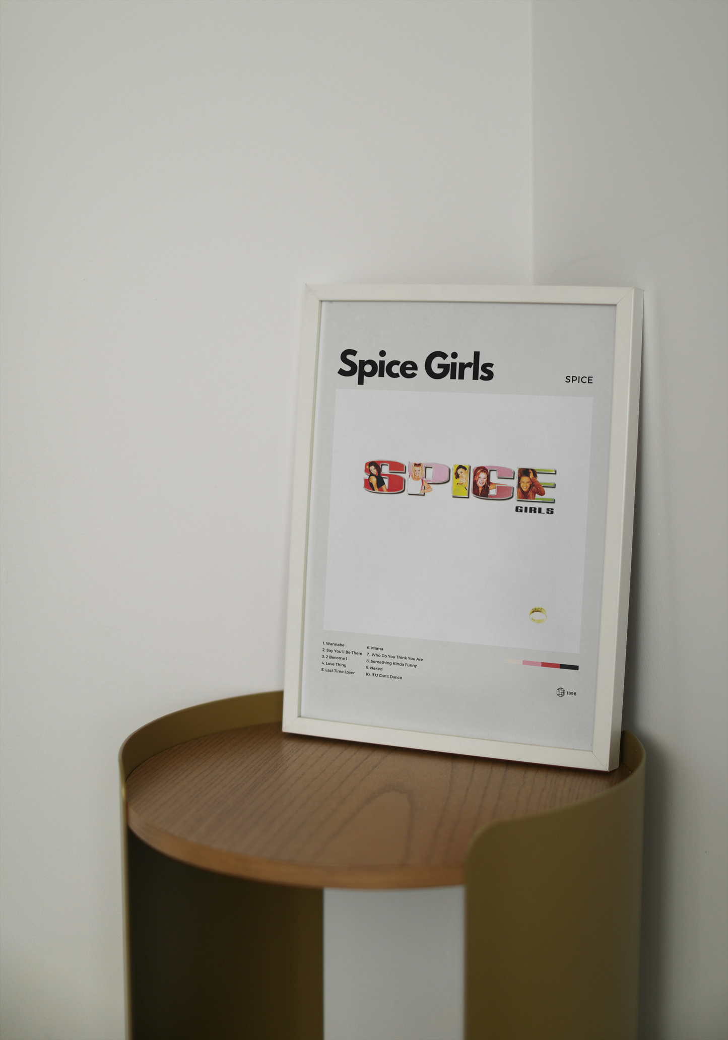 Framed 'Spice Girls' poster on a wooden shelf against a white wall