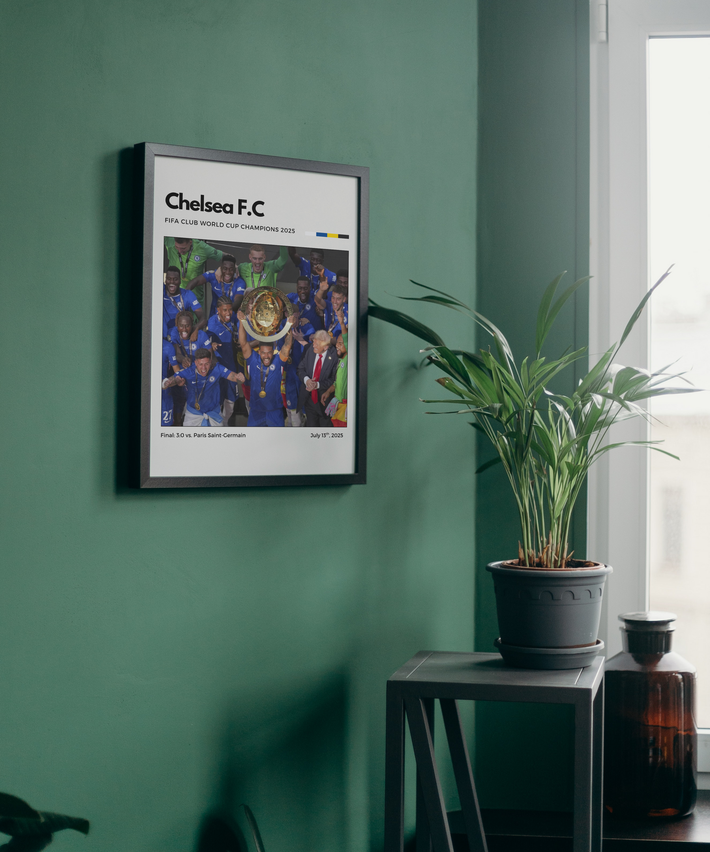 Framed Chelsea F.C. poster on a green wall with a plant and bottle in the foreground.
