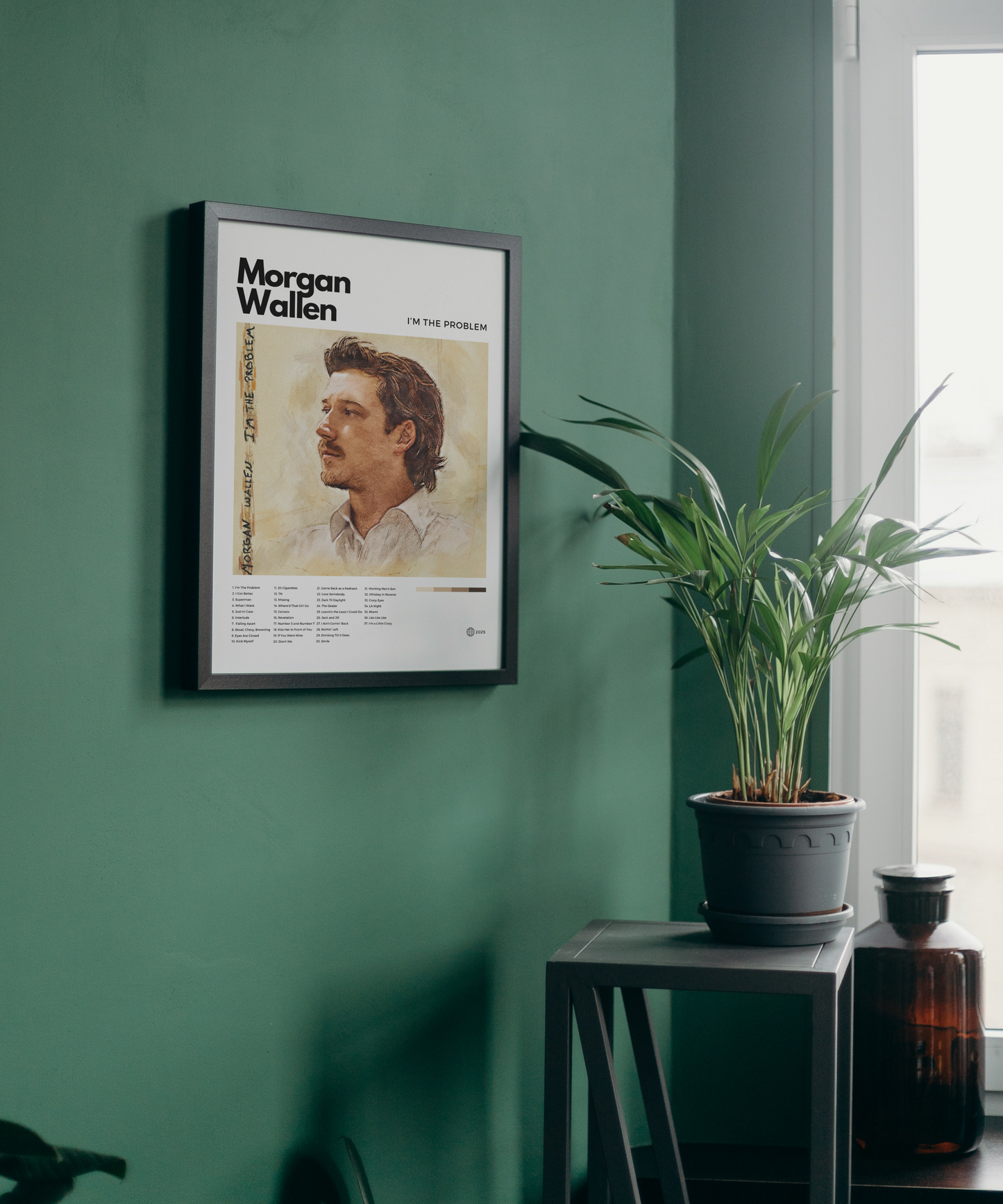 Framed poster of Morgan Wallen on a green wall with a plant and bottle in the background.