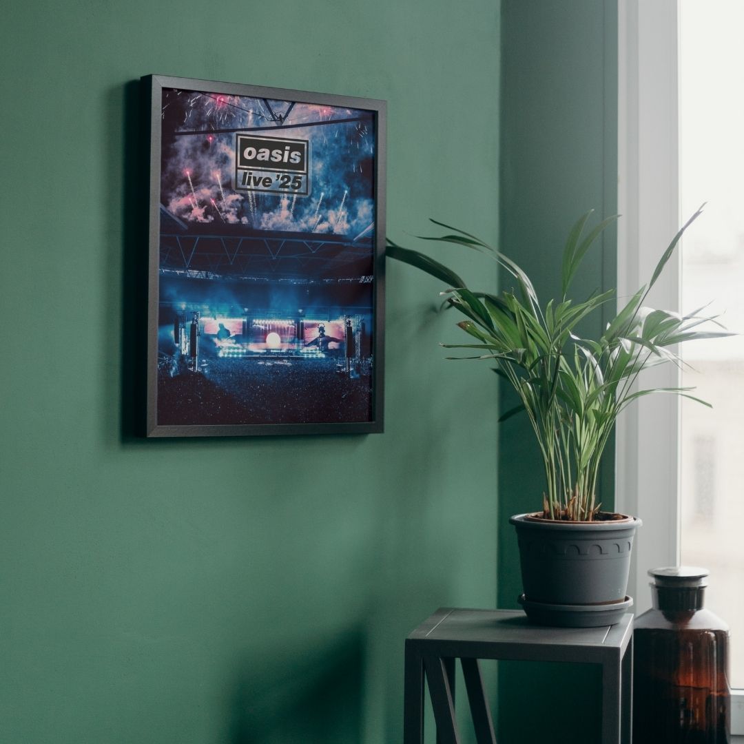 Framed concert poster of Oasis Live 25 Concert Poster. Wembley July 2025 on a green wall with a plant on a table below.