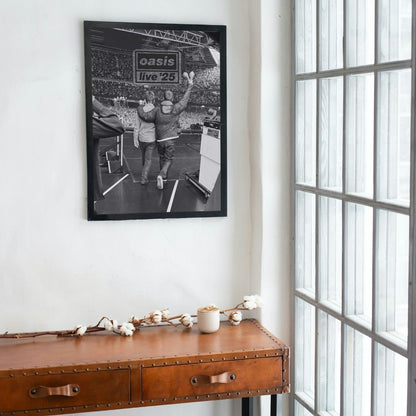 Framed concert poster of Oasis on a wall above a wooden console table.