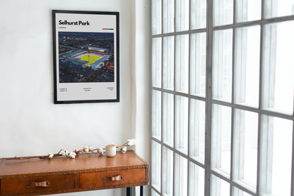 Framed artwork of a stadium on a wall next to a window