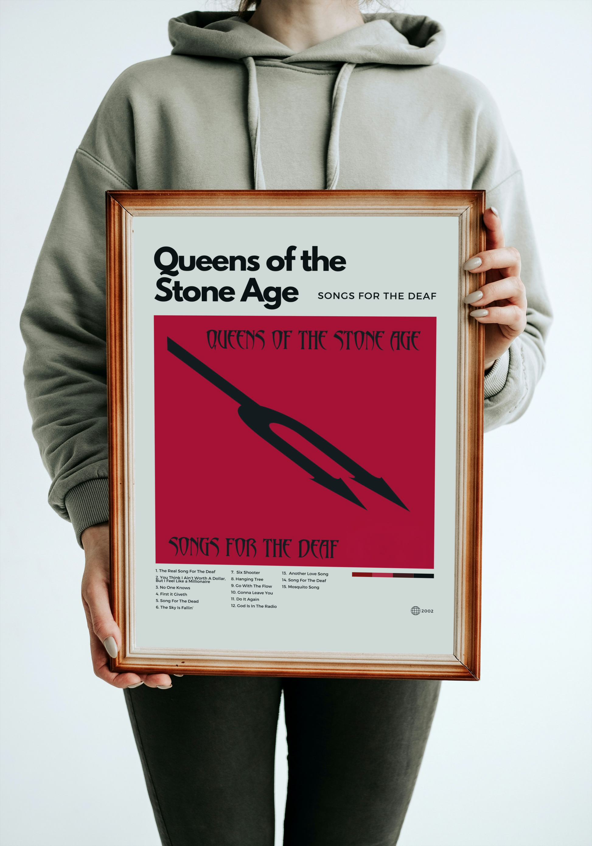 Person holding a framed album cover of 'Songs for the Deaf' by Queens of the Stone Age.