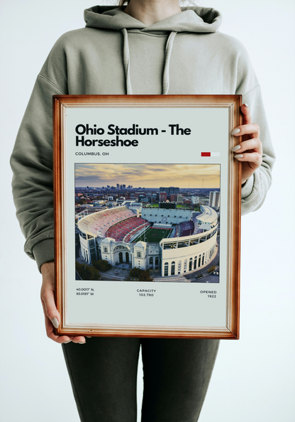 Person holding a framed poster of Ohio Stadium with a light gray hoodie.