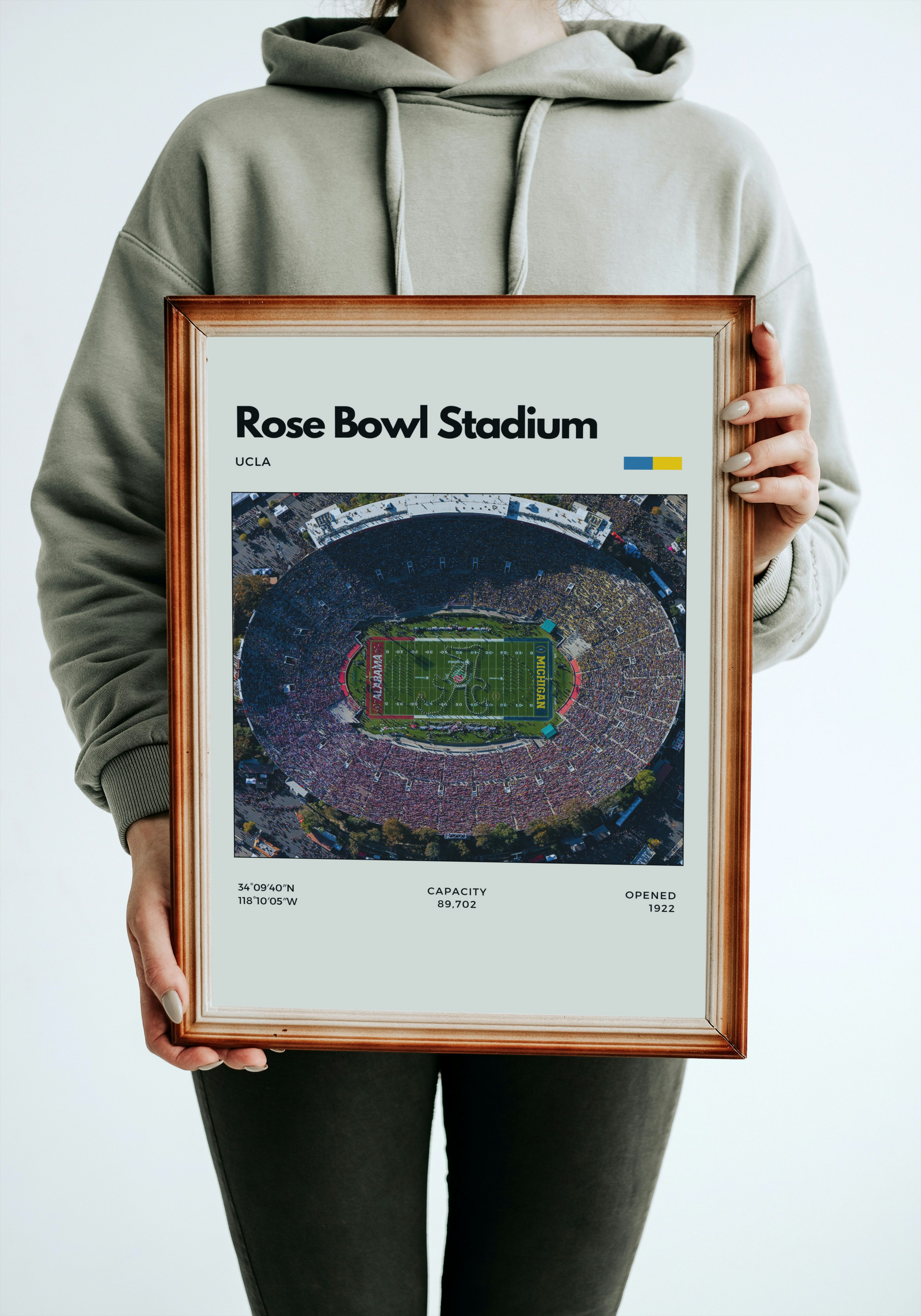 Person holding a framed print of Rose Bowl Stadium with UCLA branding.