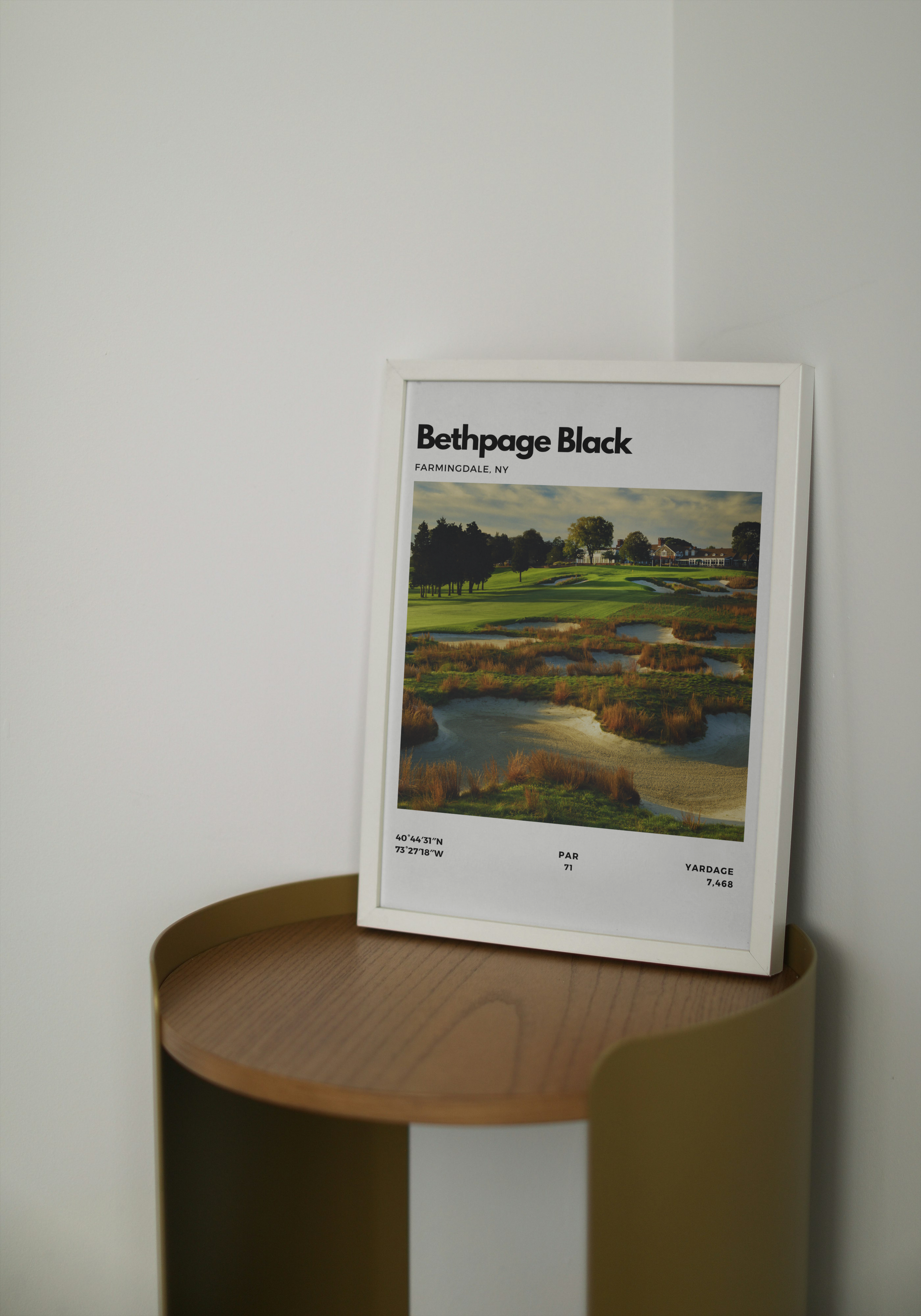 Framed poster of Bethpage Black golf course on a wooden shelf against a white wall