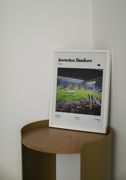 Framed poster of Juventus Stadium on a wooden shelf against a white wall