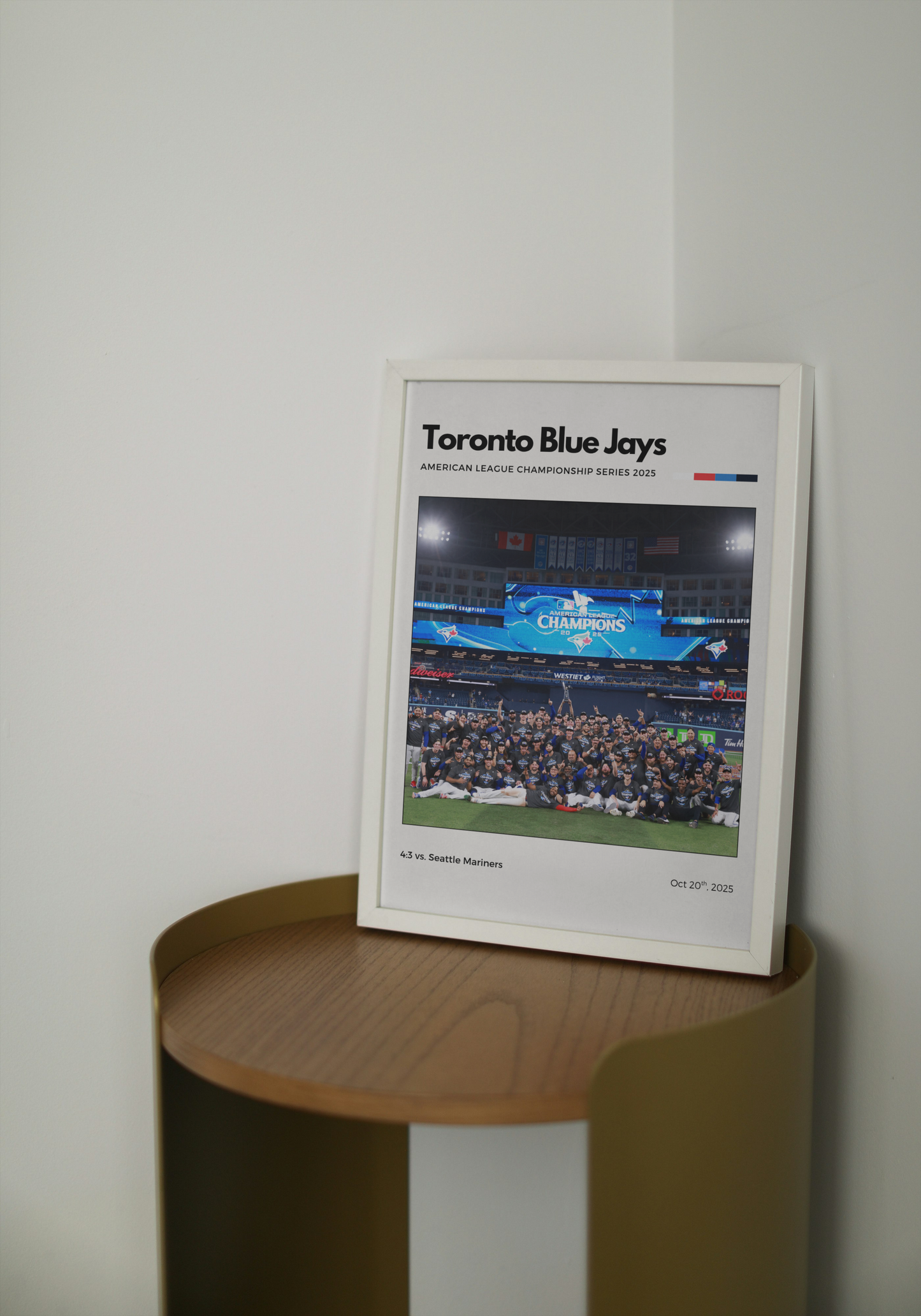 Framed Toronto Blue Jays poster on a wooden shelf against a white wall