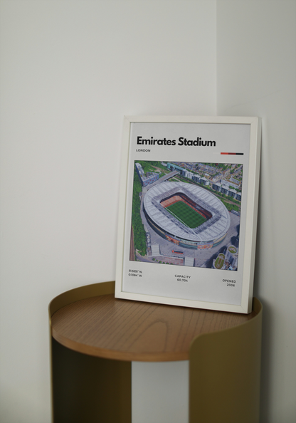 Framed poster of Emirates Stadium on a wooden shelf against a white wall