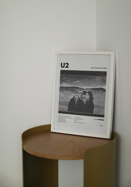 Framed U2 poster on a wooden side table against a white wall