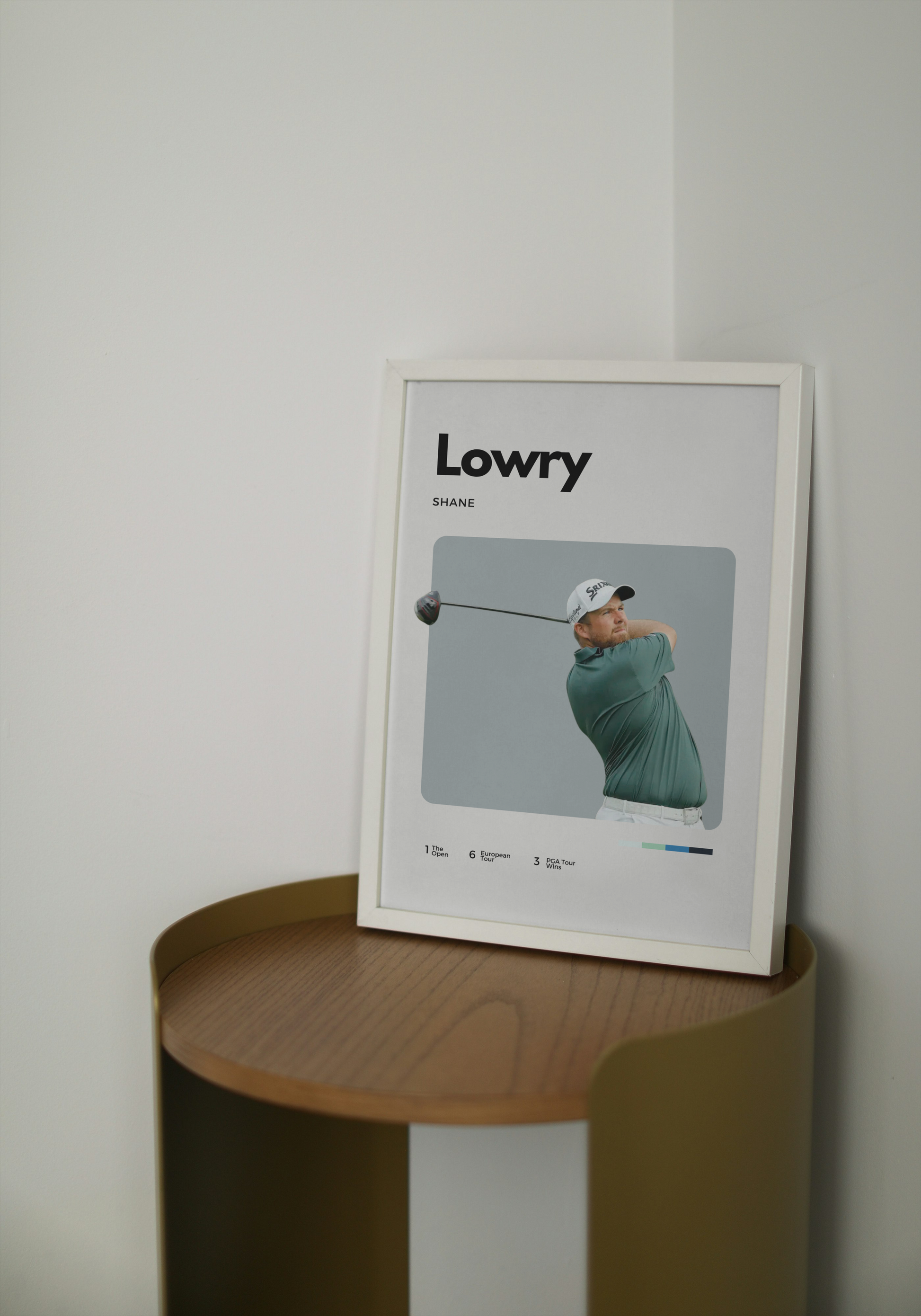 Framed picture of a golfer on a wooden side table against a white wall