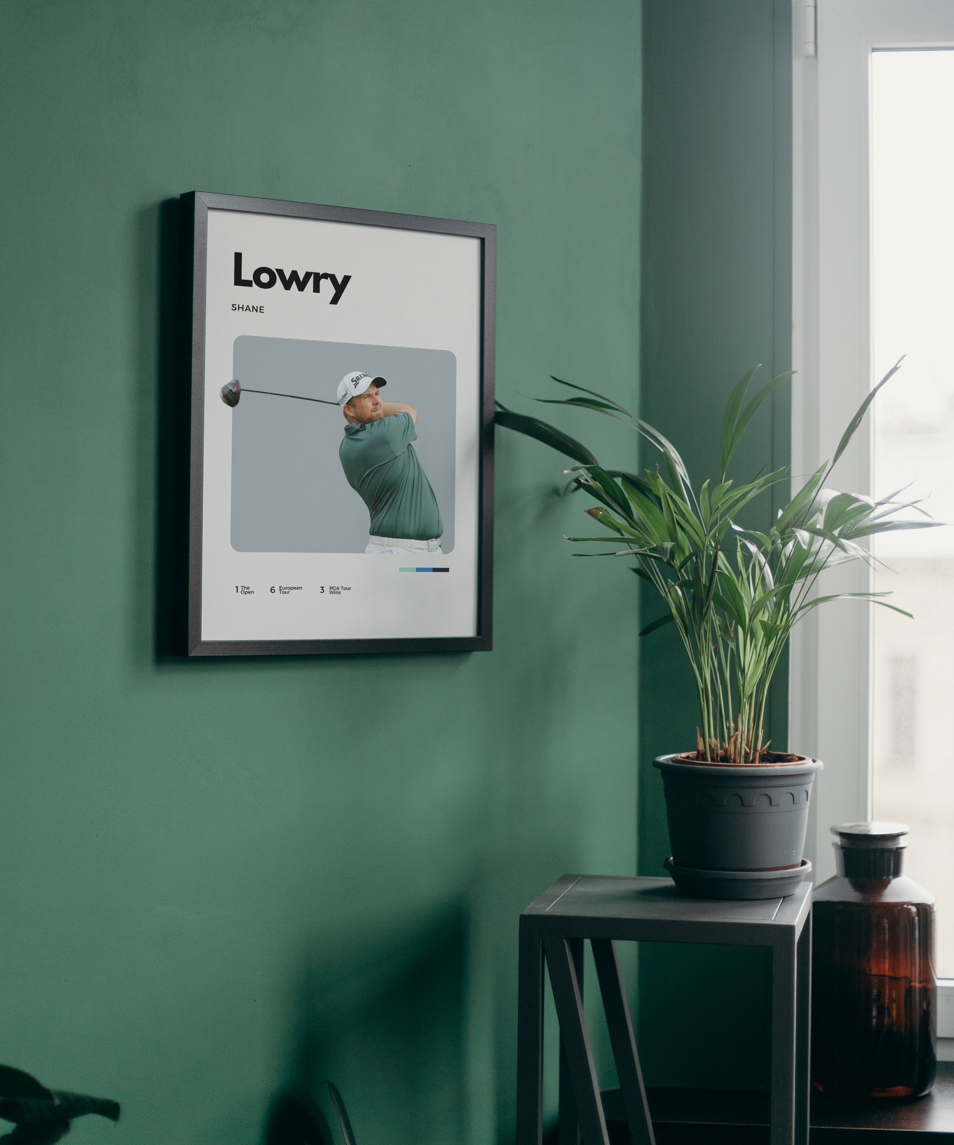 Framed poster of a golfer on a green wall with a plant and bottle in the foreground.